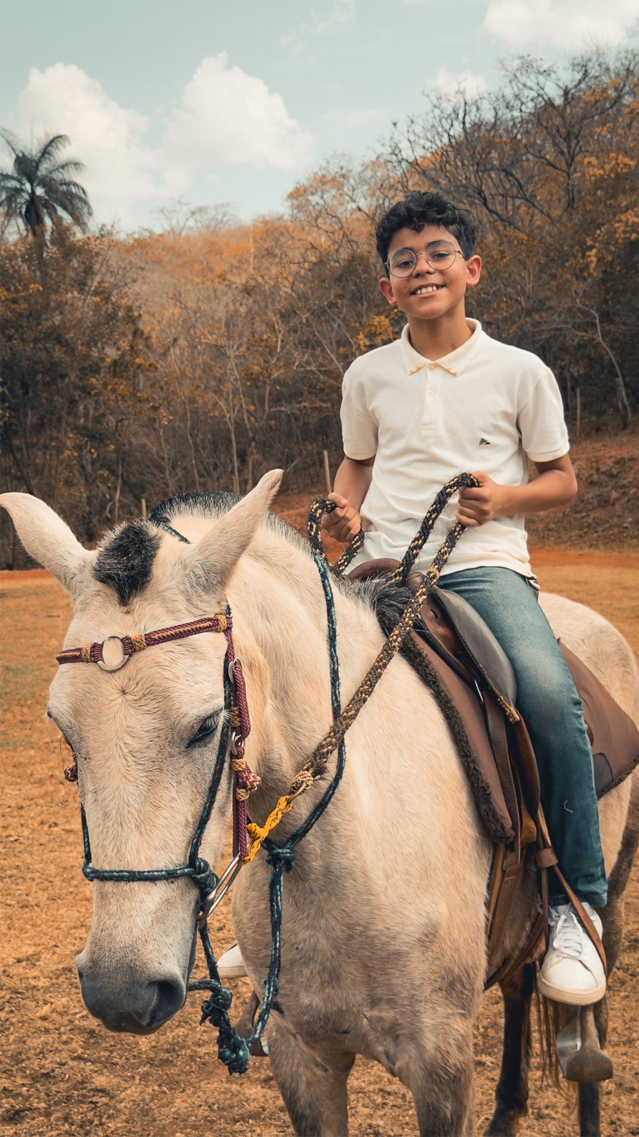 Menino sorrindo montado em um cavalo